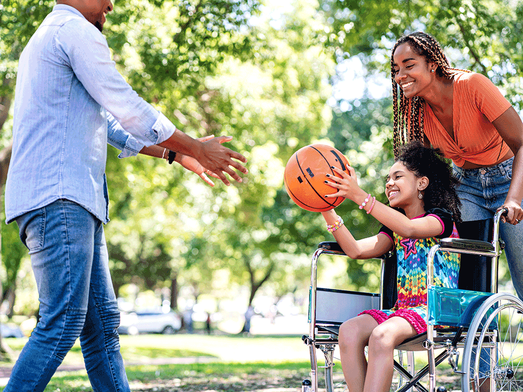 Child using a wheelchair playing basketball with adults at Aberdeen Park