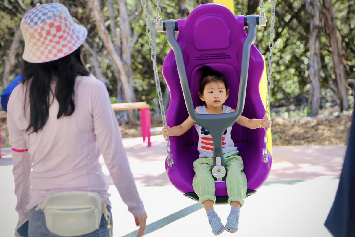 Child using purple swing at Dan Markson Park