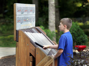 Child using outdoor musical play feature at Darrell's Dream