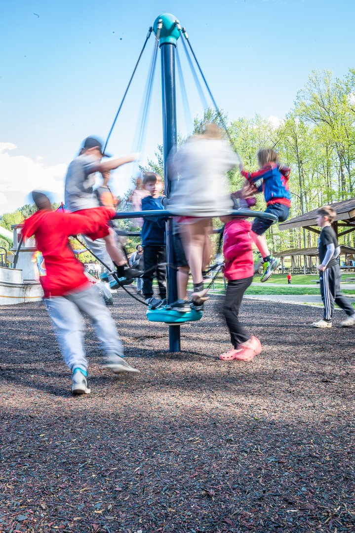Children using spinning playground equipment at a Maryland inclusive playground.