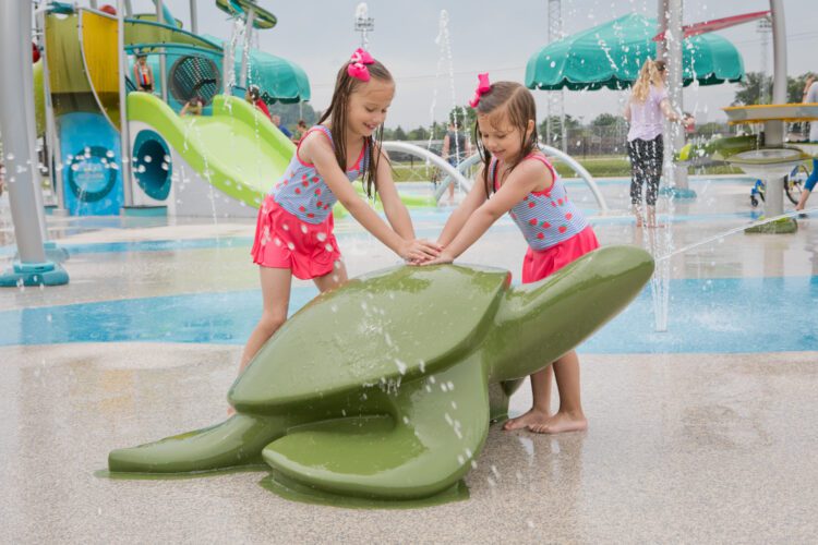 Children playing near turtle-themed splash features at Parkersburg City Park