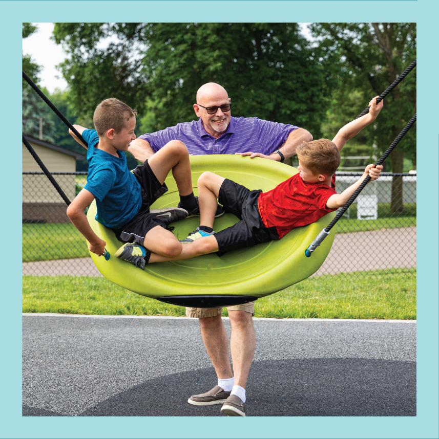 Families using accessible play equipment at Promise Park