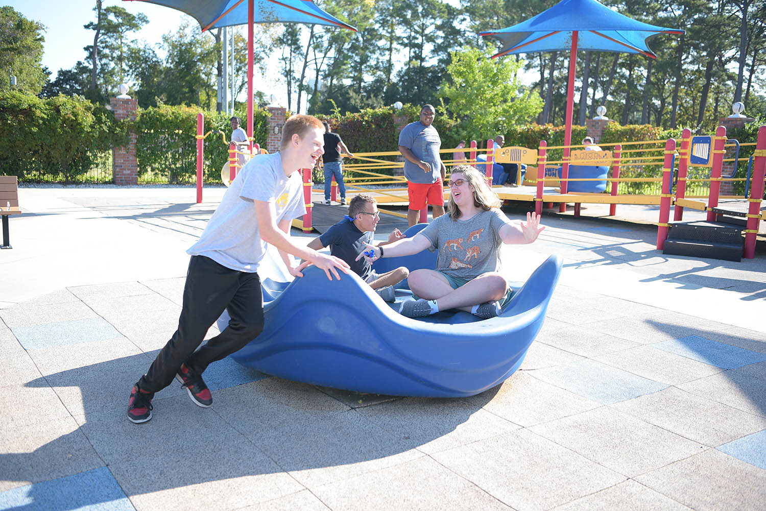 Children using an inclusive merry-go-round style playground feature