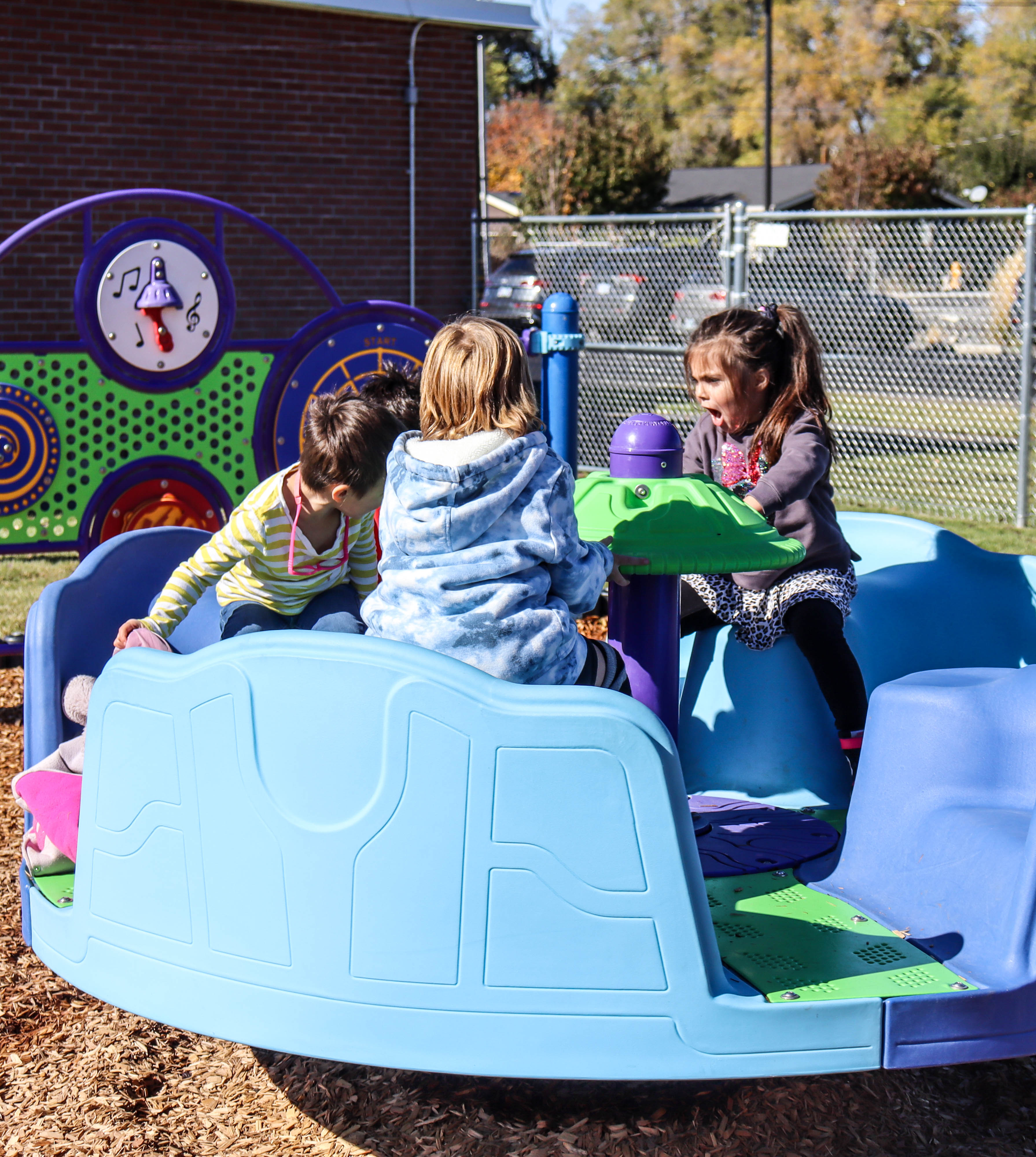 Students on adaptive merry-go-round at Stearns Elementary