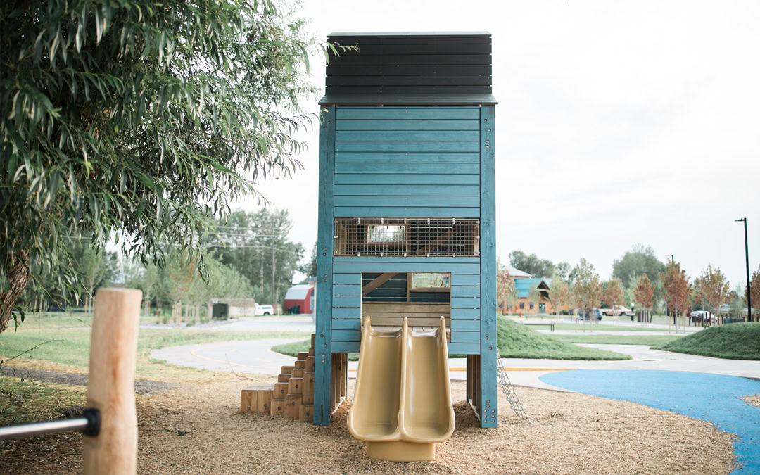 Blue playground tower with double slides and accessible path at Story Mill