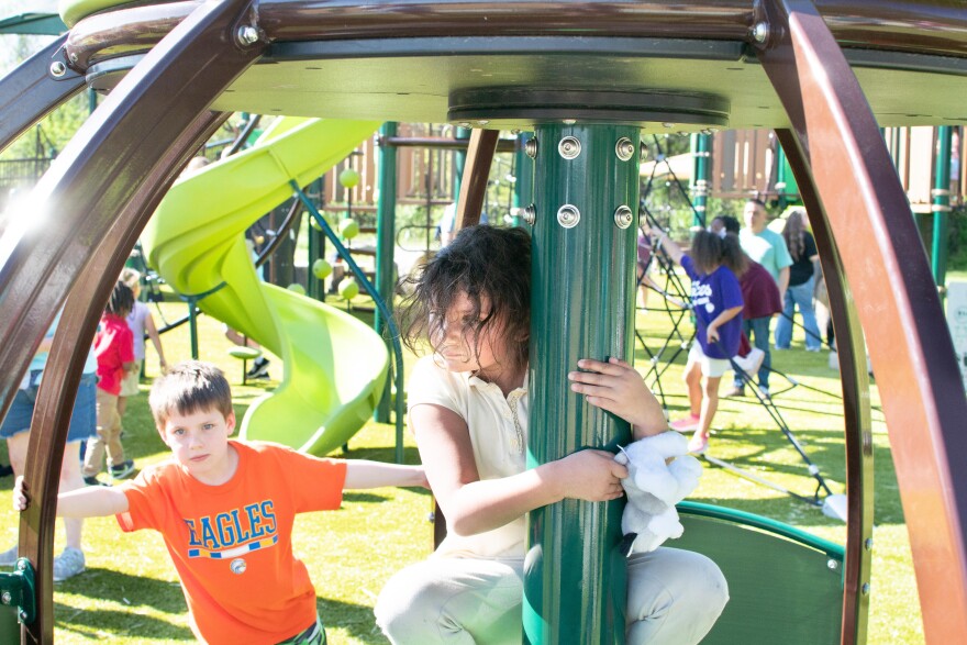 Children using the ground-level accessible we-go-round at Wesselman Park