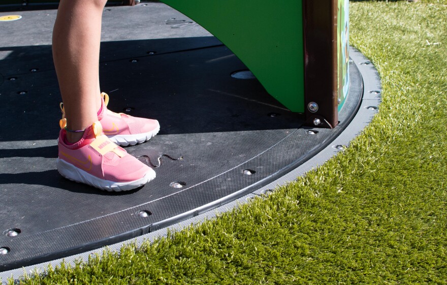 Soft turf surrounding the accessible merry-go-round at Wesselman Park