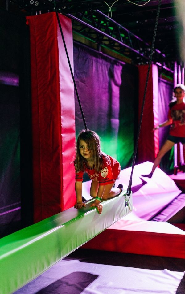 Child navigating an indoor obstacle challenge at Adrenaline Monkey