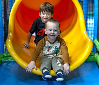 Children at the base of a bright yellow slide at Ahoy Kitsap Playland