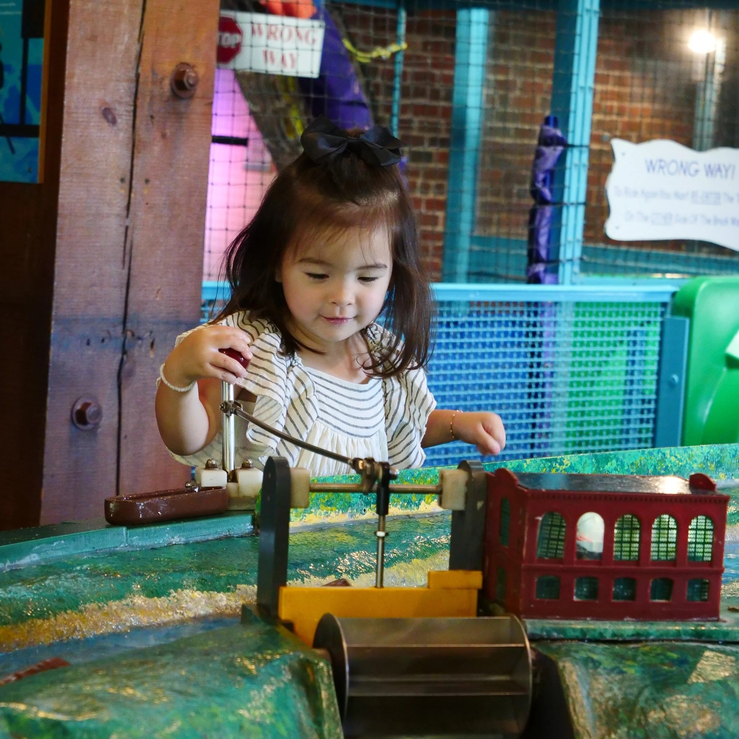 Young child at a colorful interactive exhibit inside Amazement Square.