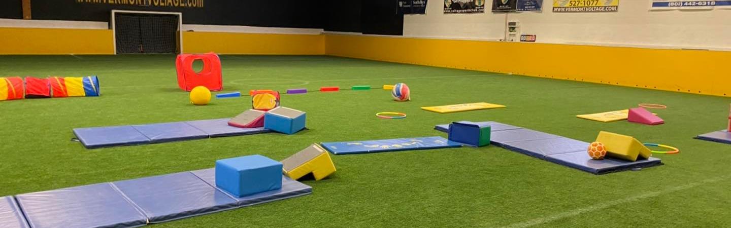 Tumbling Tots setup with mats, foam blocks, and play gear on indoor turf