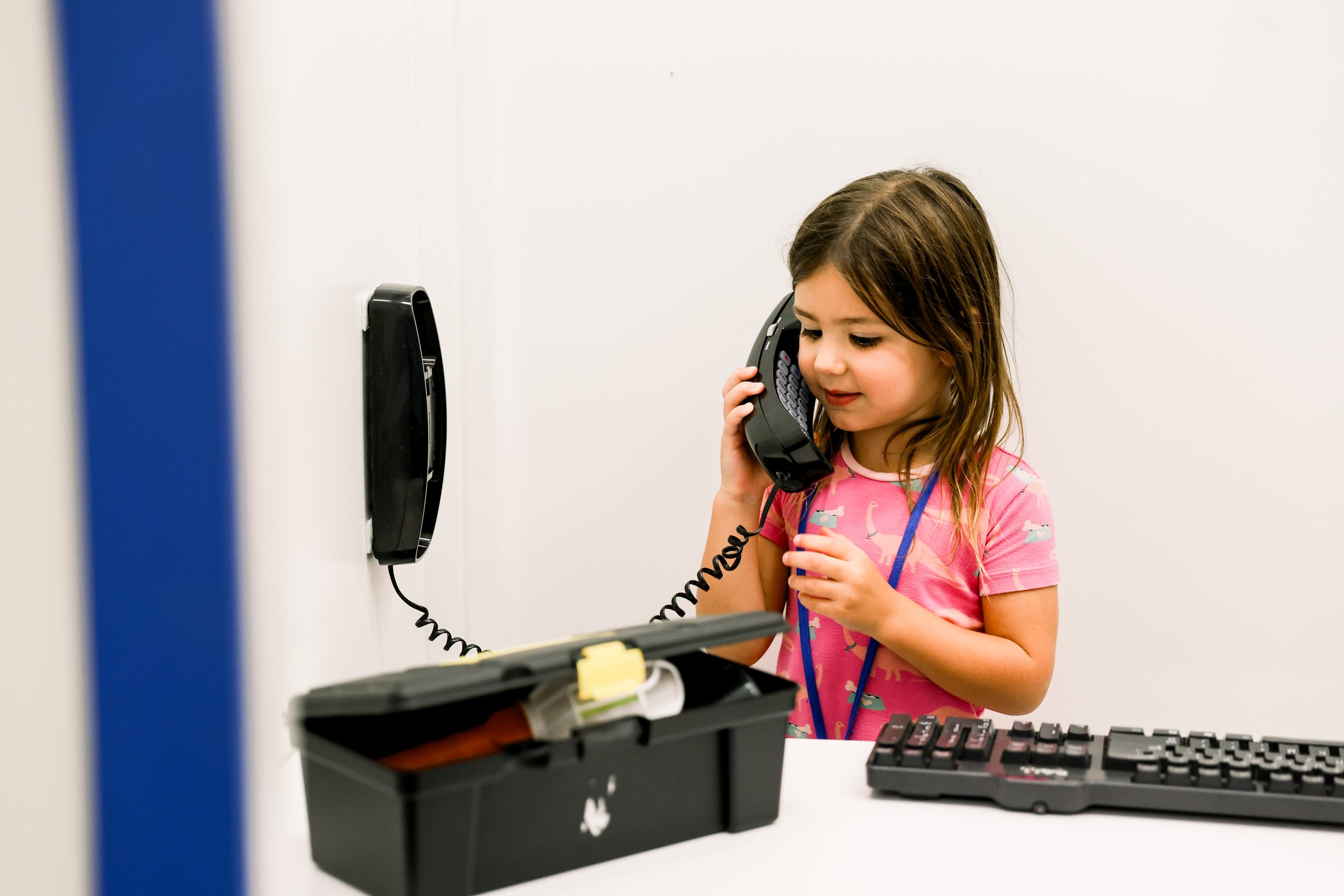 A child using a play telephone inside BUILDville