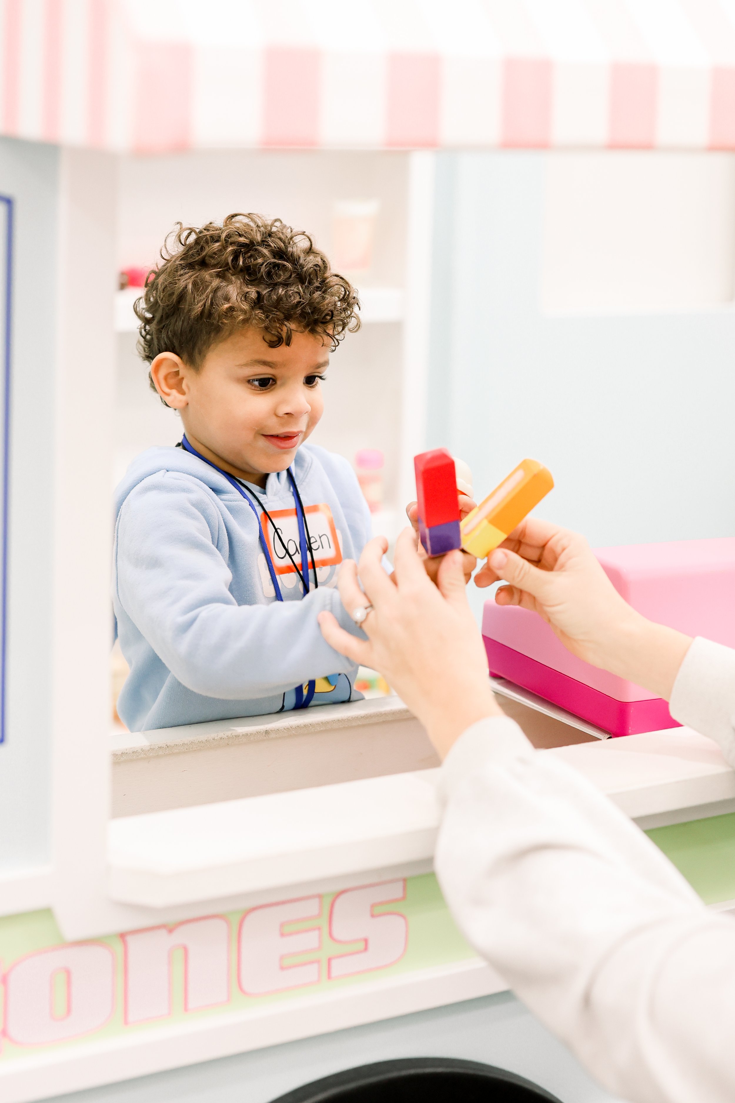 Children playing at a child-sized checkout area inside BUILDville