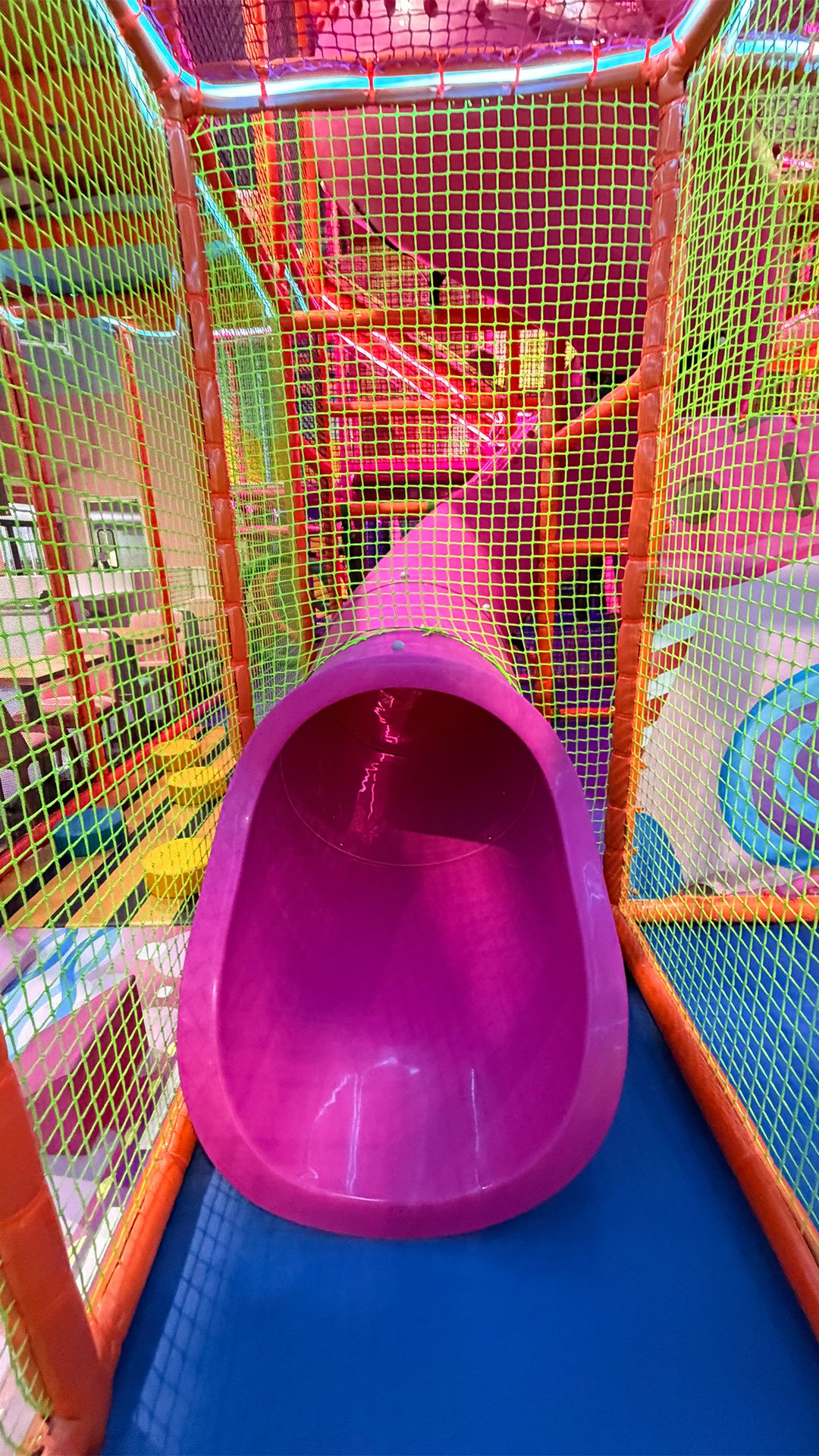Bright pink tube slide inside the play structure at Candeeland Modesto.
