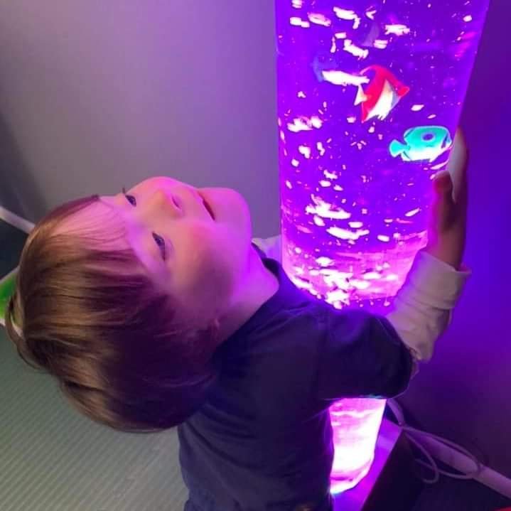 Young child looking at a glowing sensory bubble tube.