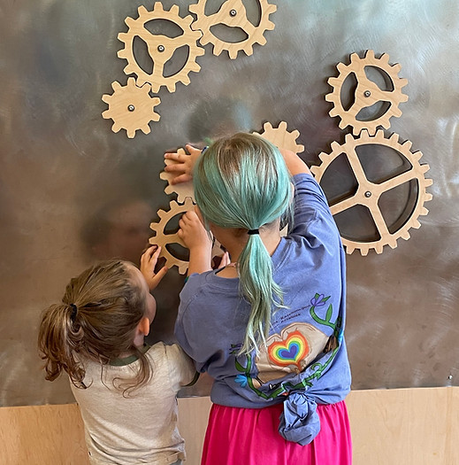 Children exploring a gear wall exhibit.