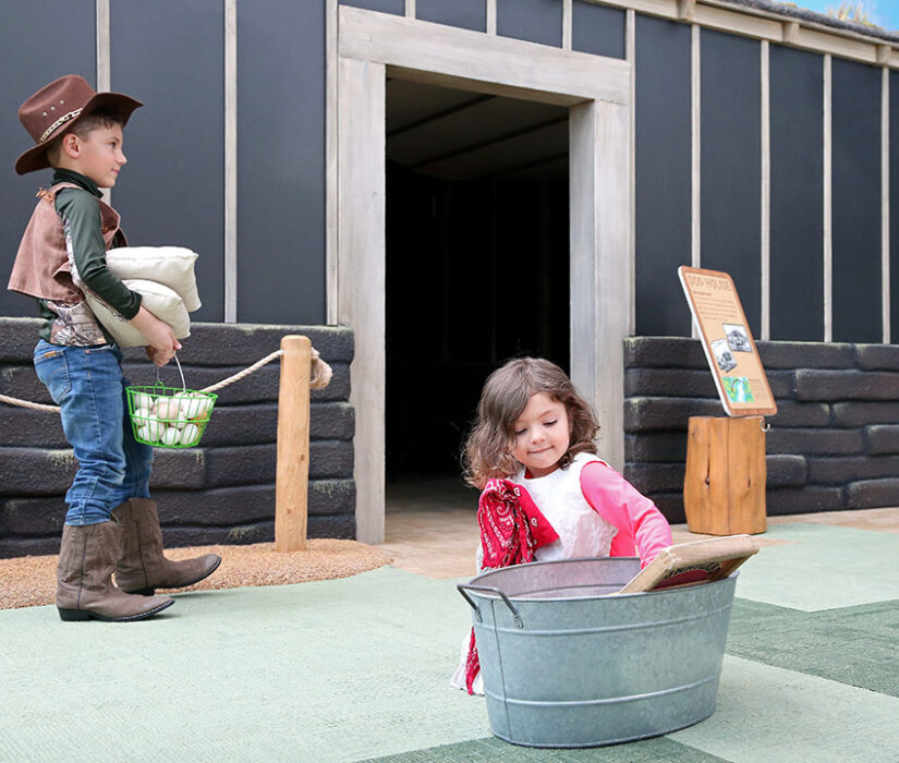 Children playing outside the indoor Sod House exhibit at the Children's Museum of South Dakota.