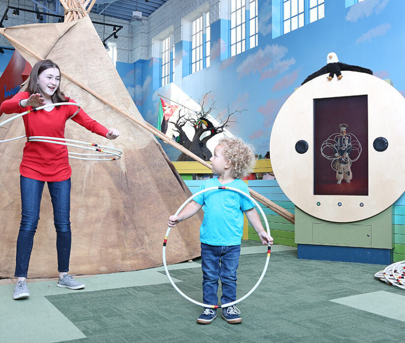 Children using hoops near the indoor tipi exhibit at the Children's Museum of South Dakota.