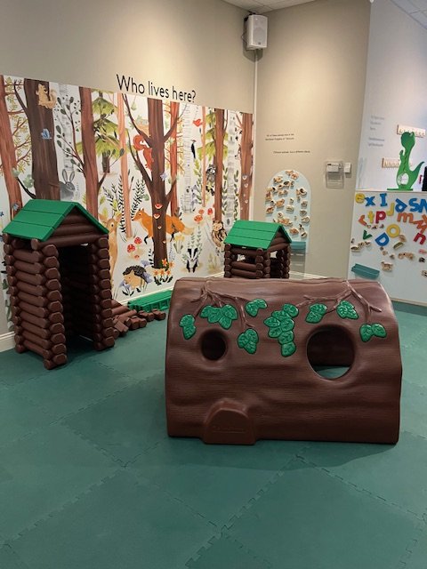 Forest-themed play area with crawl-through log climbers at the Children's Museum of the Northeast Kingdom.