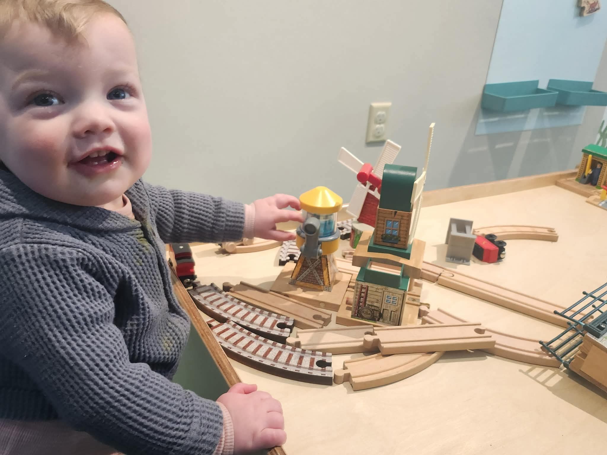 Toddler exploring a wooden train table exhibit at the Children's Museum of the Northeast Kingdom.