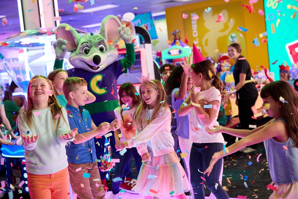 Kids celebrating and playing during a Chuck E. Cheese party.