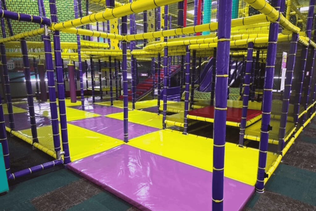 Chuck E. Cheese indoor play structure with superhero-themed climbing areas.