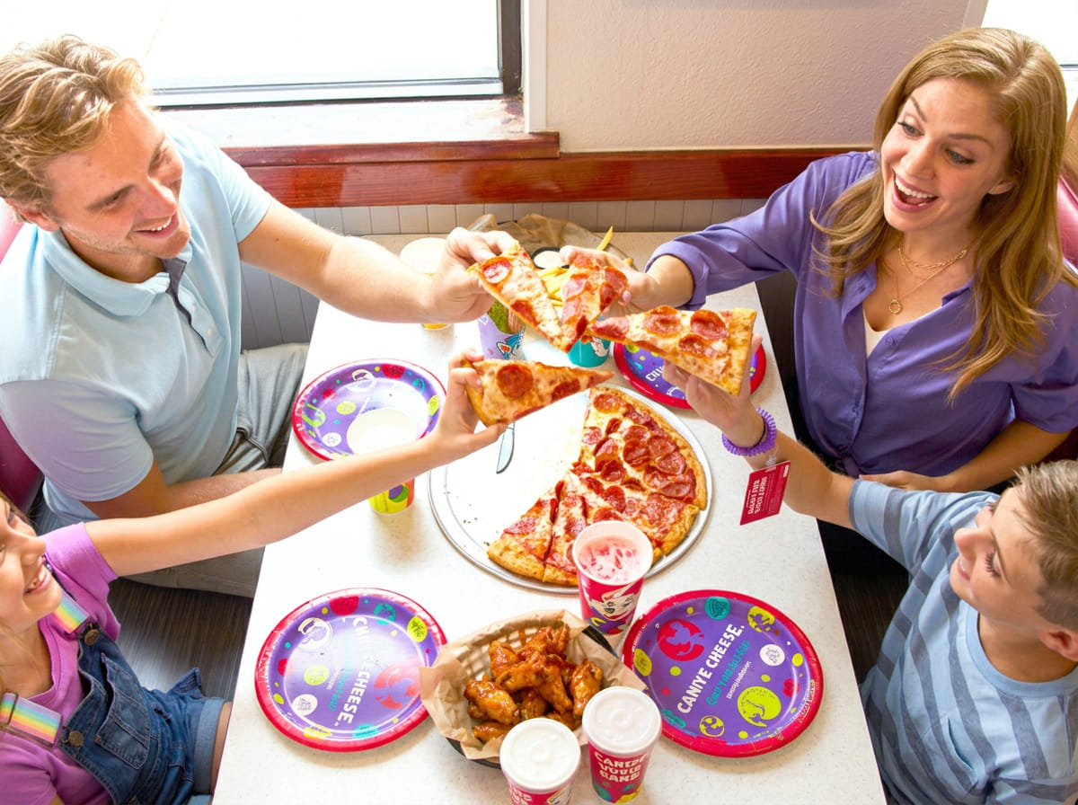 Family seated together with pizza at Chuck E. Cheese.