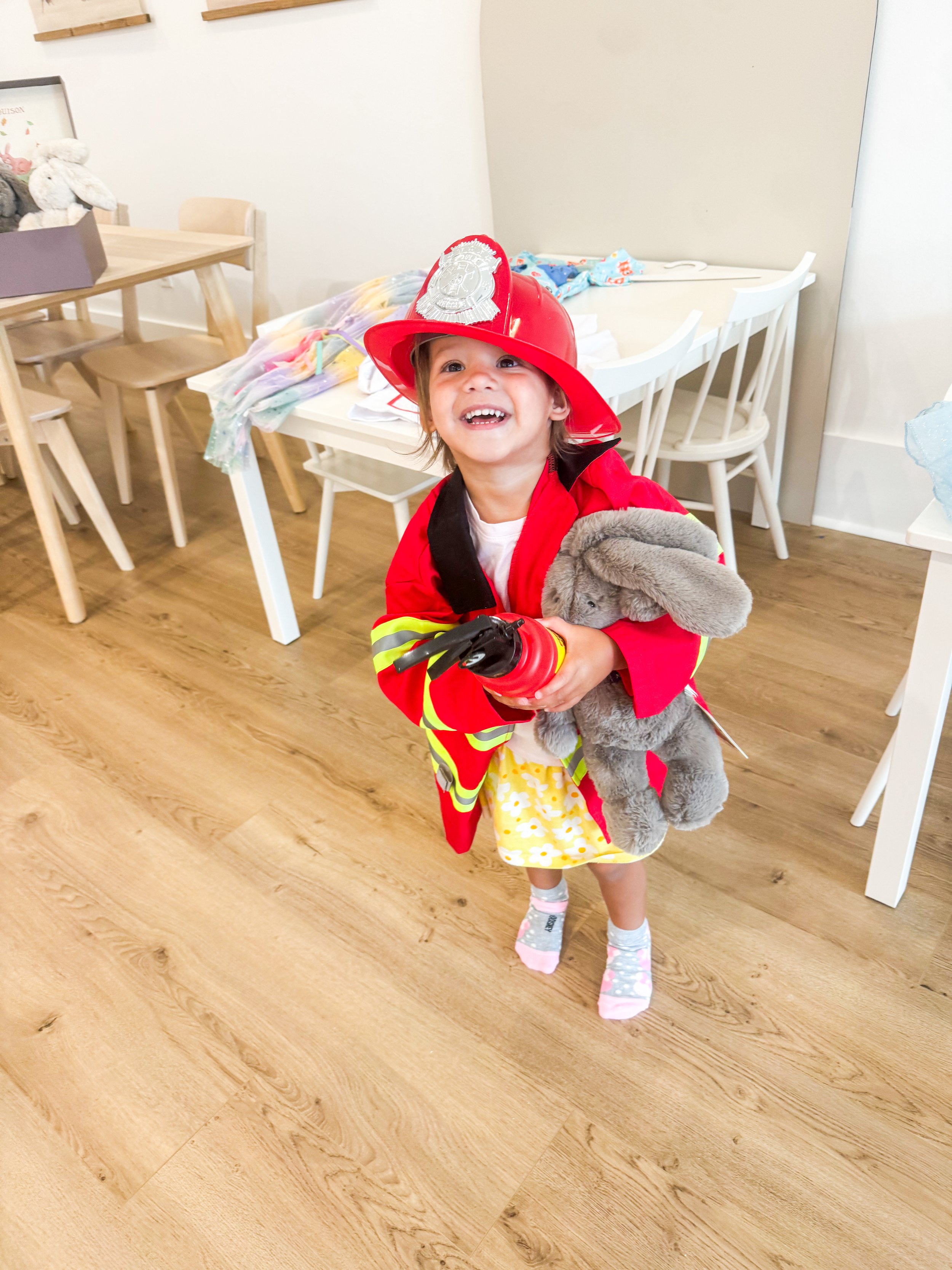 Child exploring pretend play and table activities inside the studio.