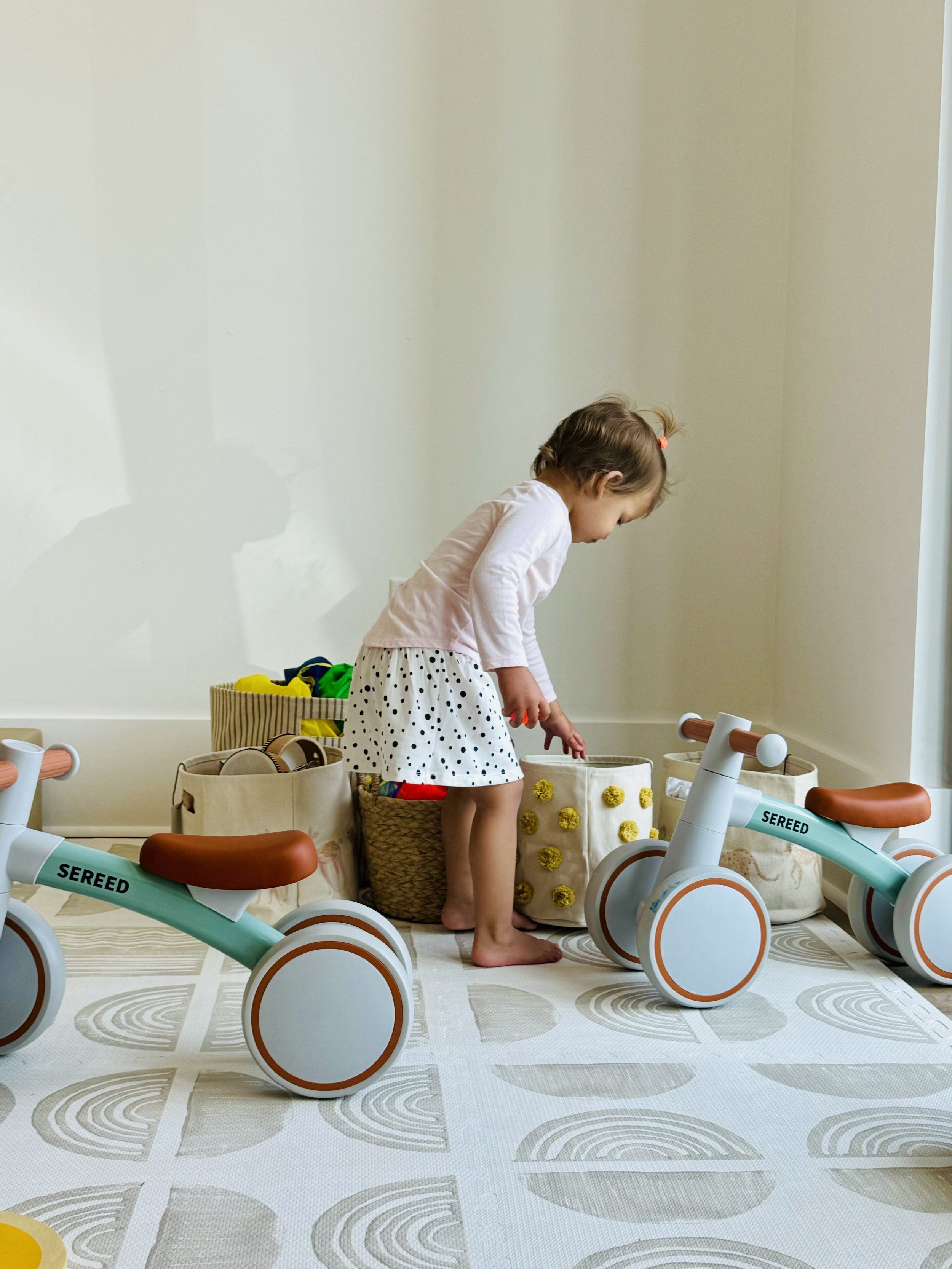 Toddler exploring a calm play nook with ride-on toys and baskets at Create & Play Club.