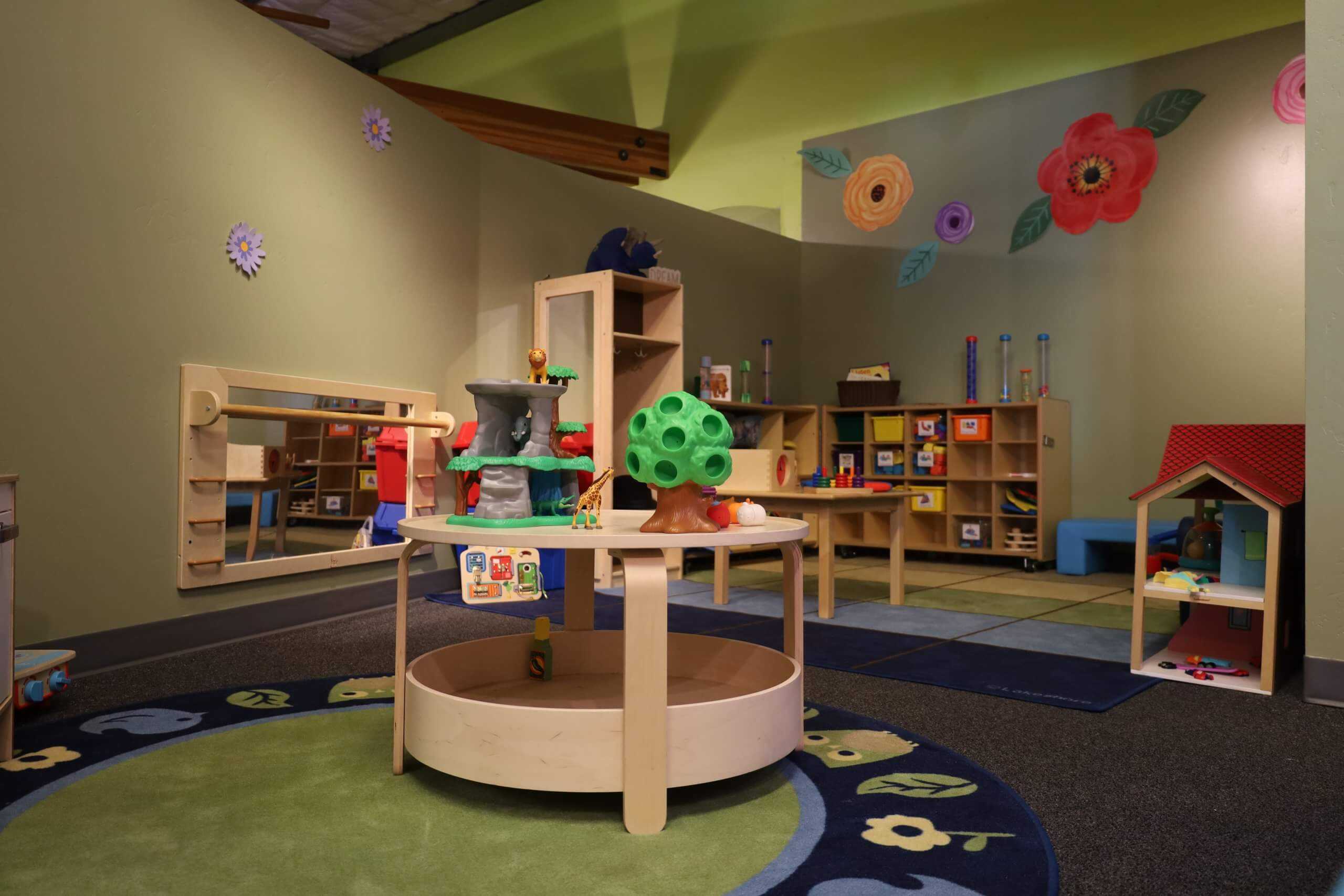 Dedicated Tot Spot play room with toddler-sized toys, shelving, and soft flooring at CRR Discovery Museum.