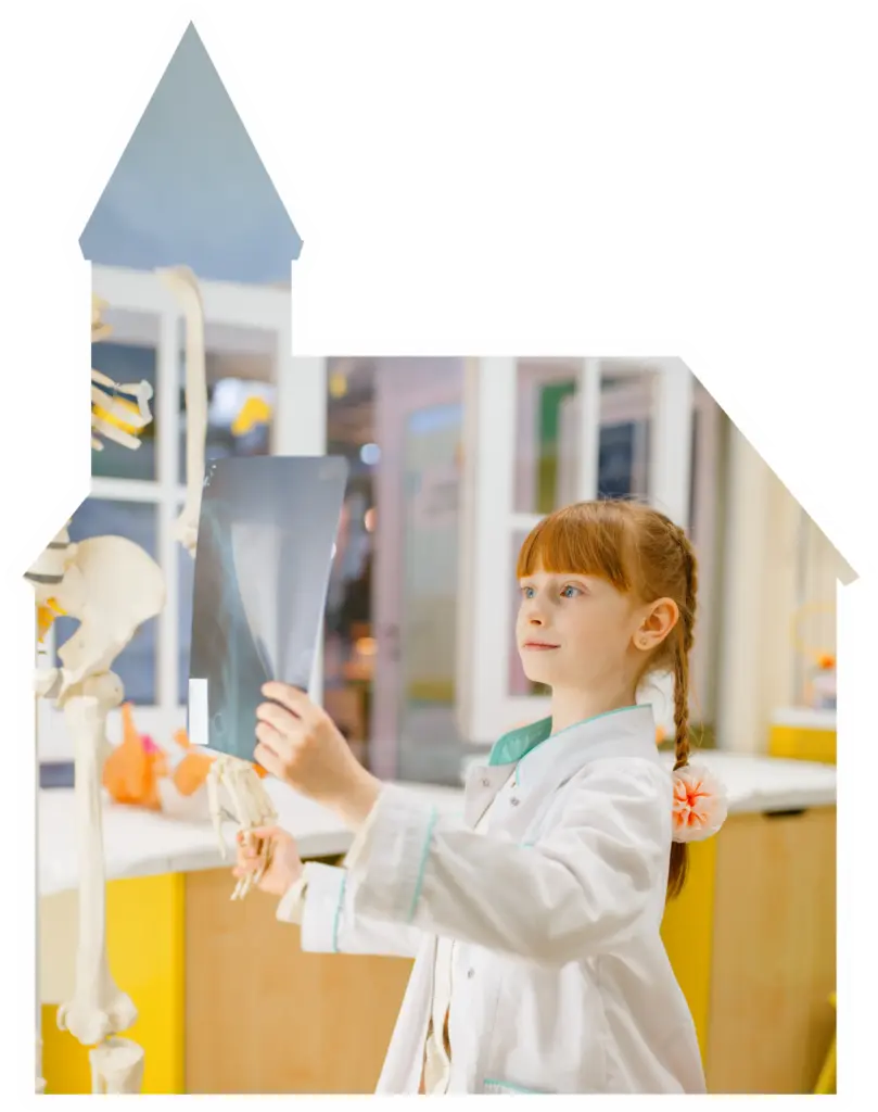 Child holding an x-ray in a pretend clinic area at Curiosity Avenue.