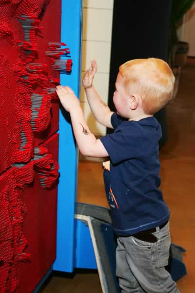 Child using the giant pin wall at Curious Kids' Discovery Zone.