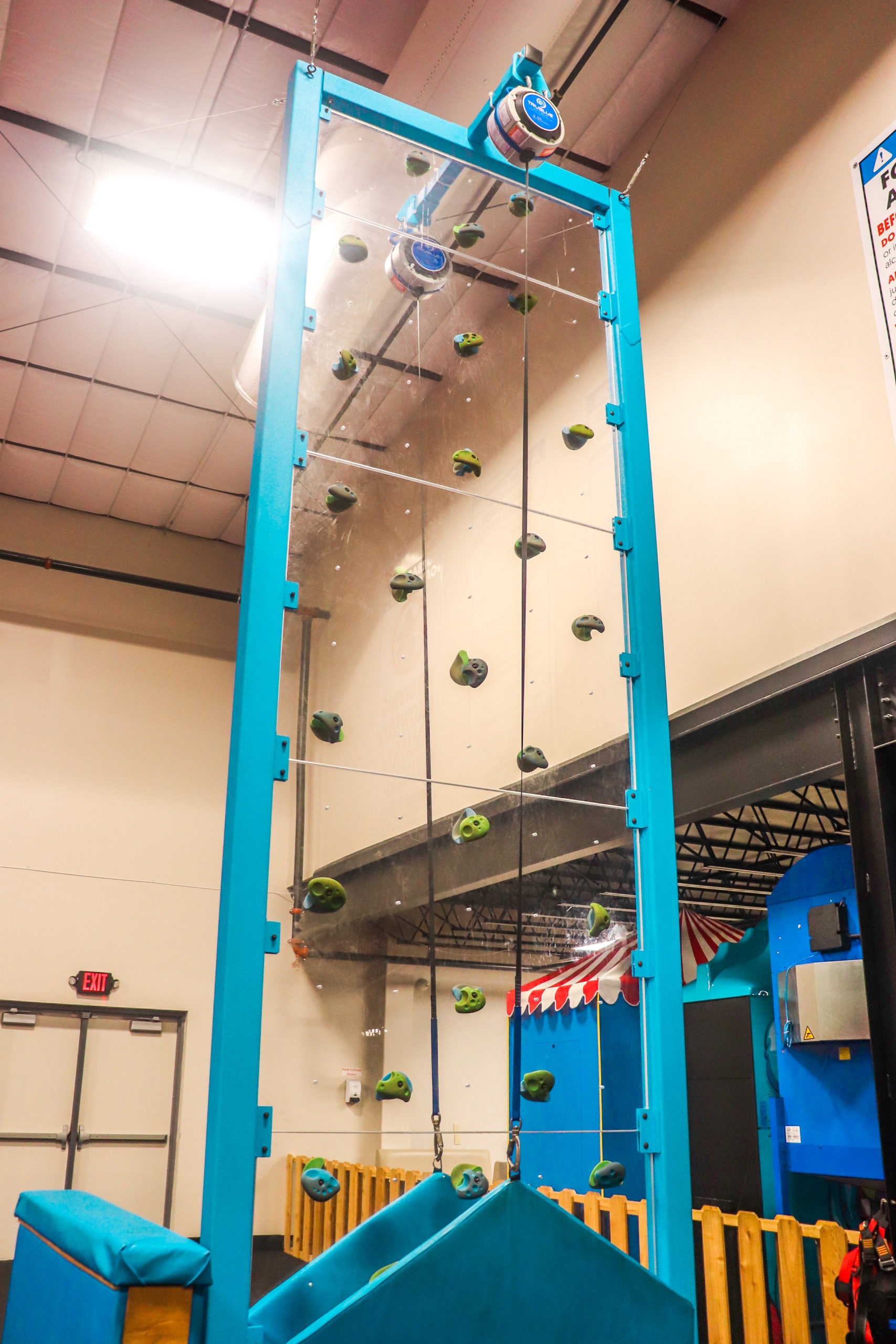 Tall blue climbing wall with auto-belay-style setup at Da Swamp.