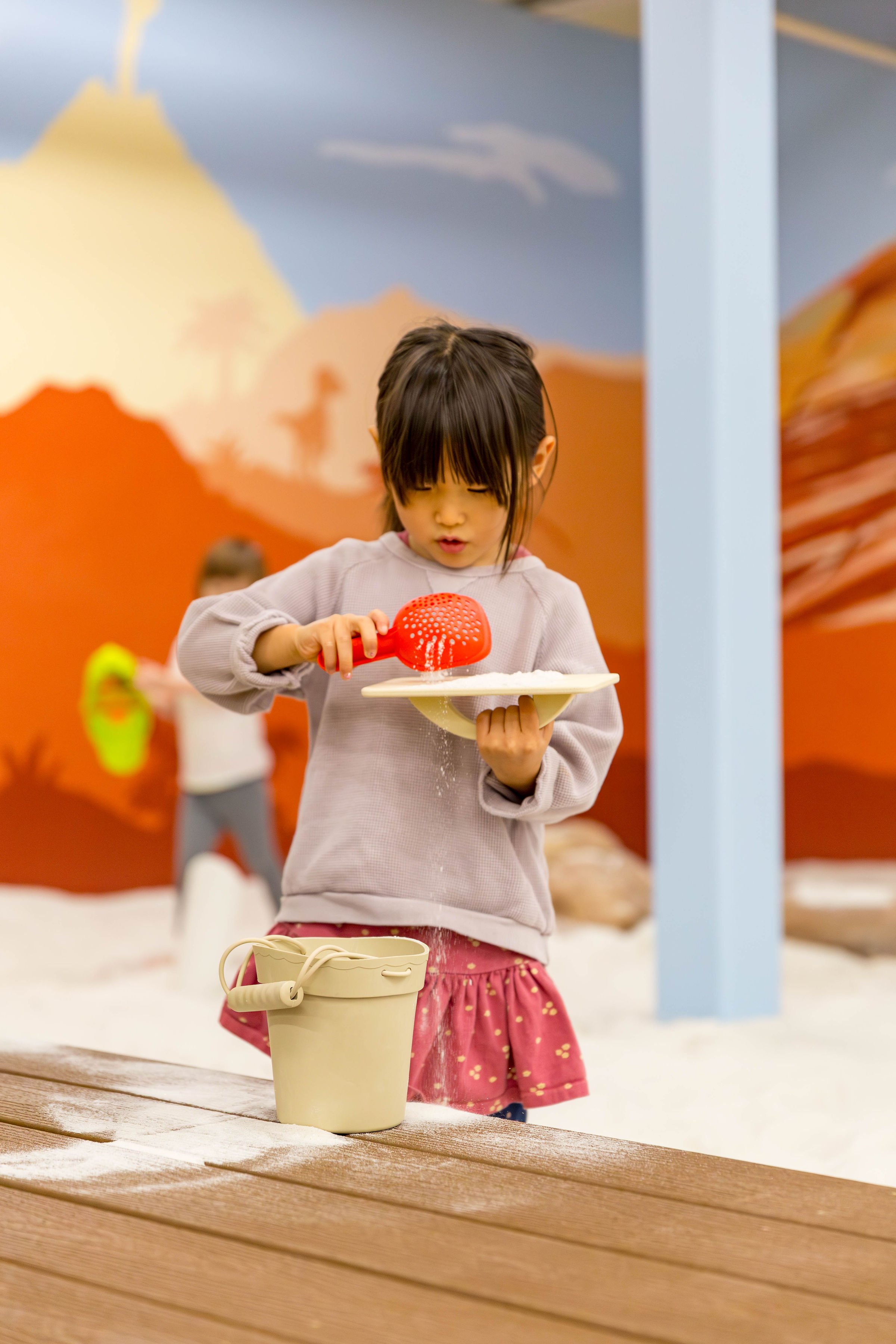 Children digging and playing in the indoor sand area at DiG PDX.