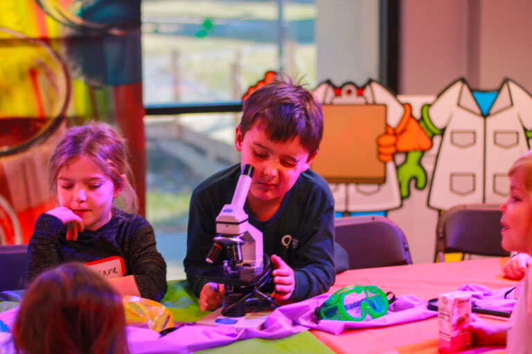 Children using a microscope during a birthday activity at Don Harrington Discovery Center.