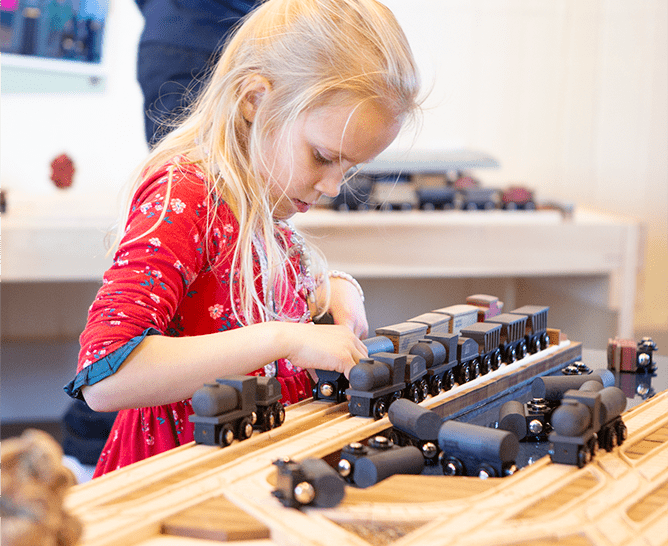 Child building and arranging wooden trains at Edwardsville Children's Museum.