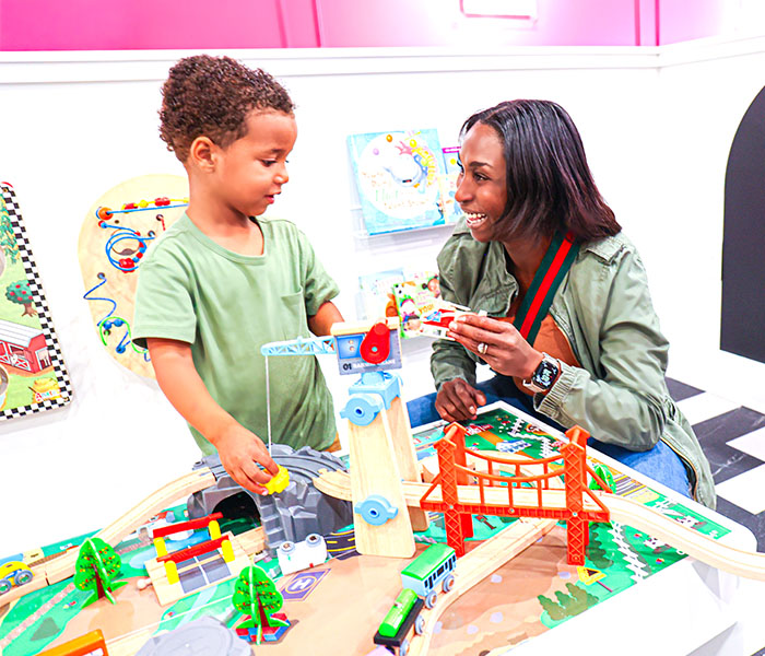 Caregiver and child playing at a train table inside Electric Donuts Play Cafe.