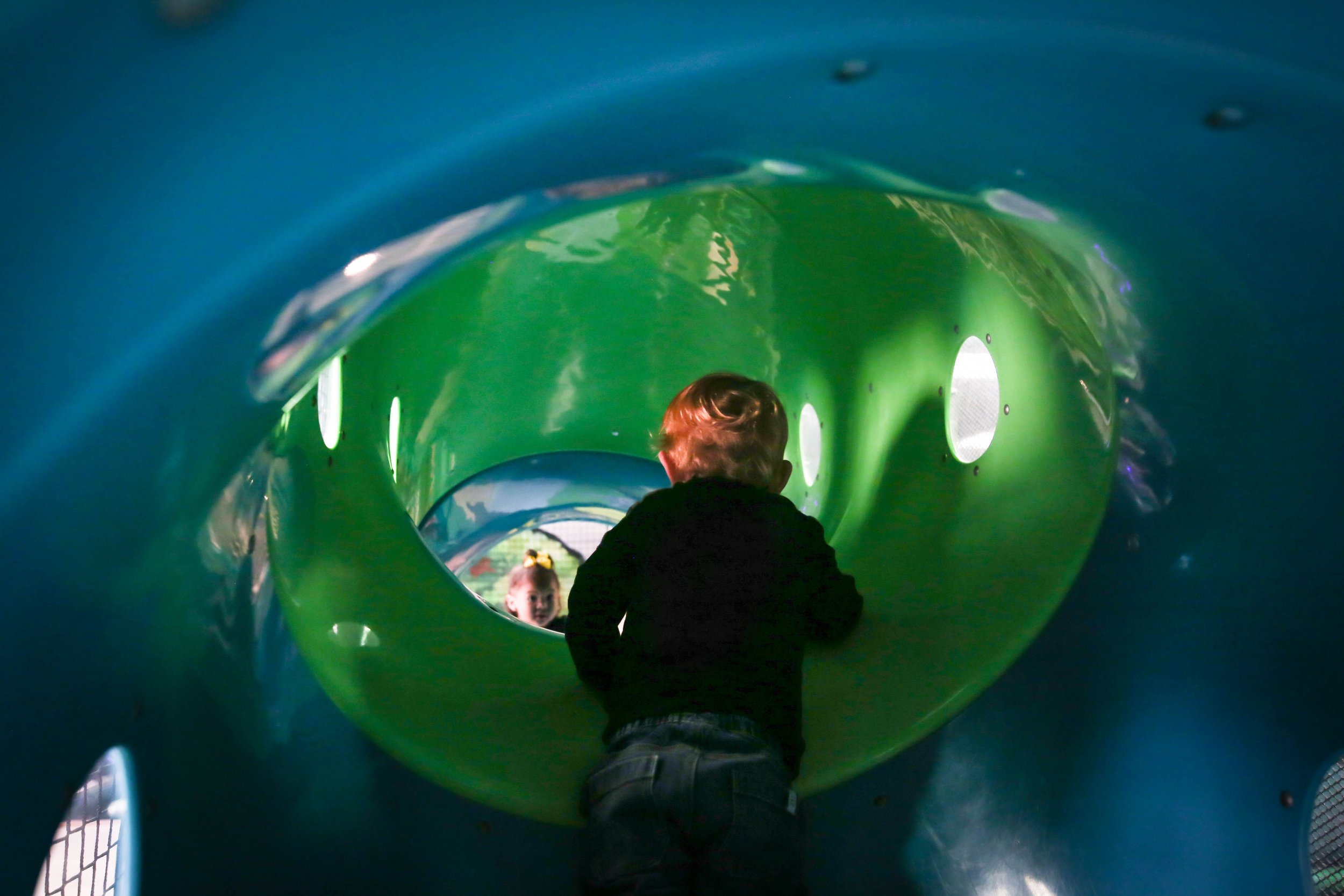 Child crawling through a rounded tunnel play feature at Enchanted Elk Grove