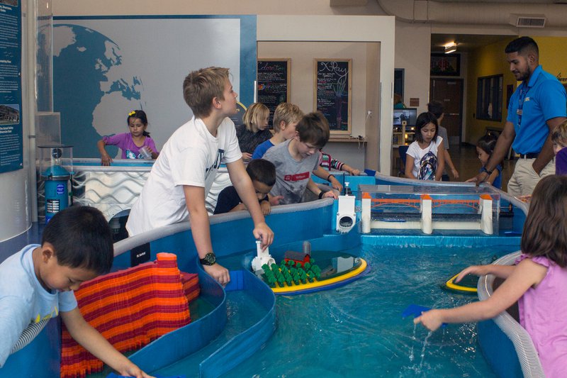 Children playing at a hands-on water table exhibit inside EUREKA! McConnell Science Museum.