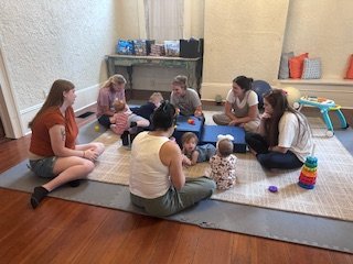 Caregivers and children gathered on the floor at Family Social Club