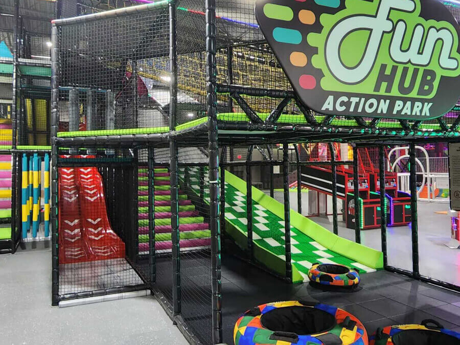 Multi-level indoor playground with slides at FunHub Action Park.