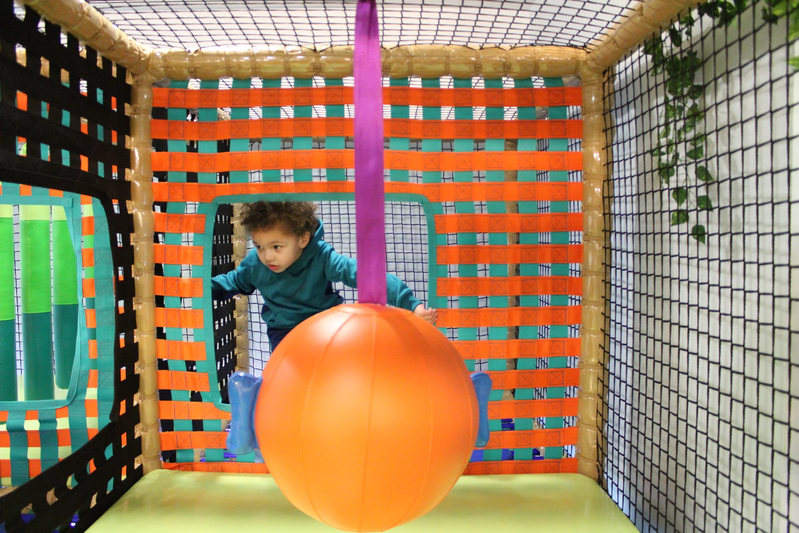 A child exploring a suspended-ball obstacle inside Funzy Play Newport.