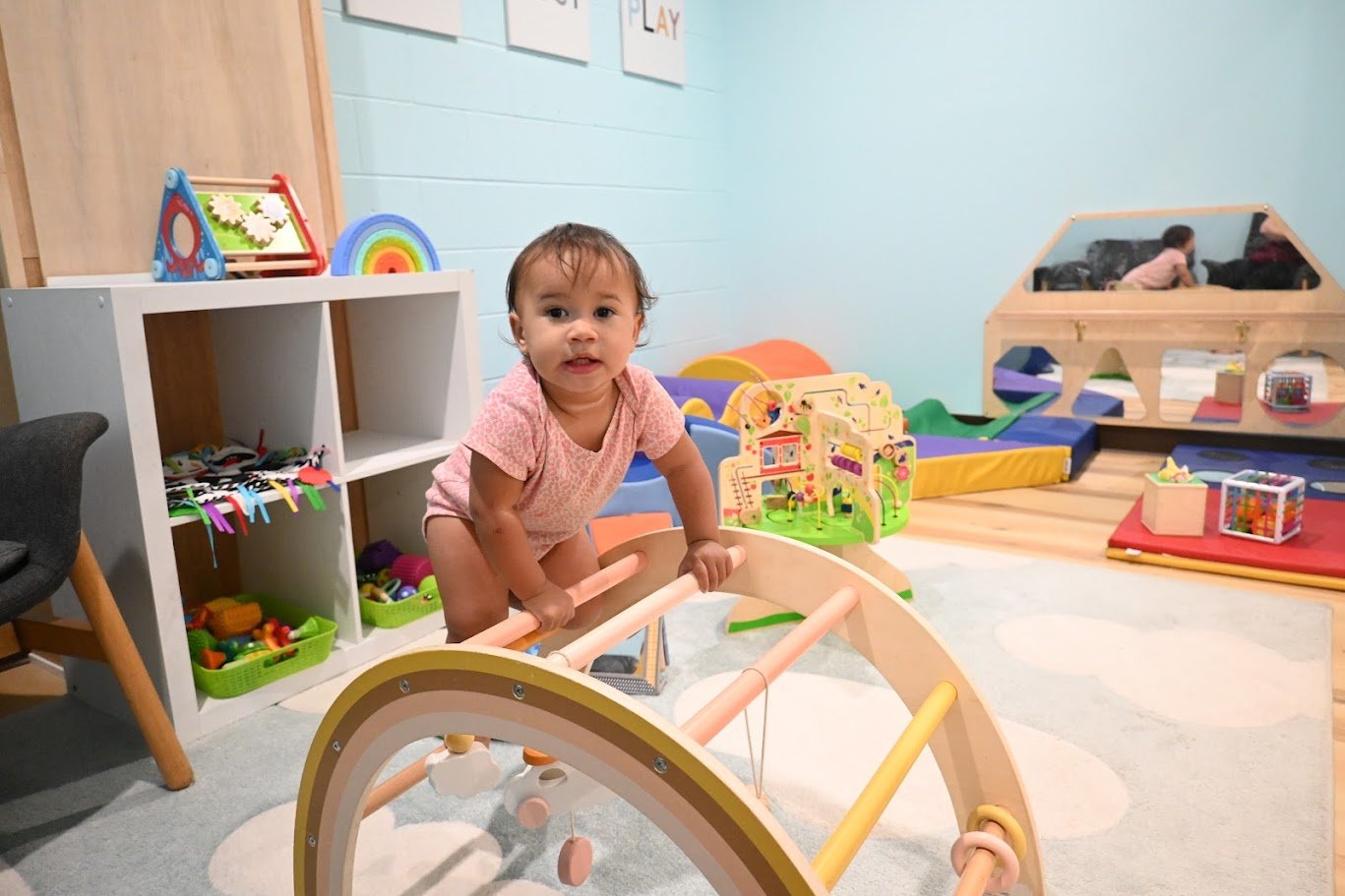 Soft baby-and-toddler area with low climbing equipment, mirror, and activity toys.