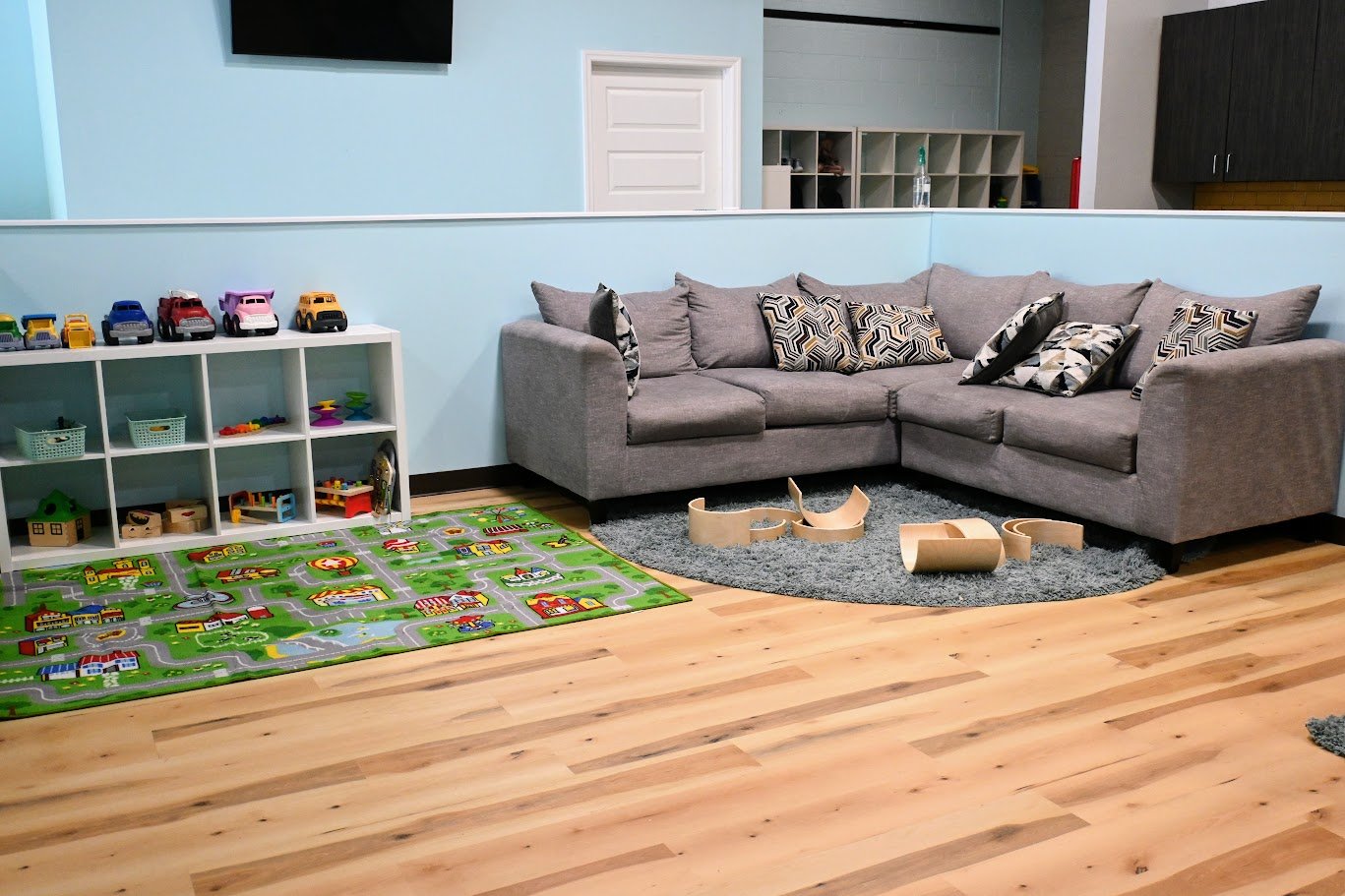 Caregiver seating area beside open floor play space and toy shelves at GentleHands.