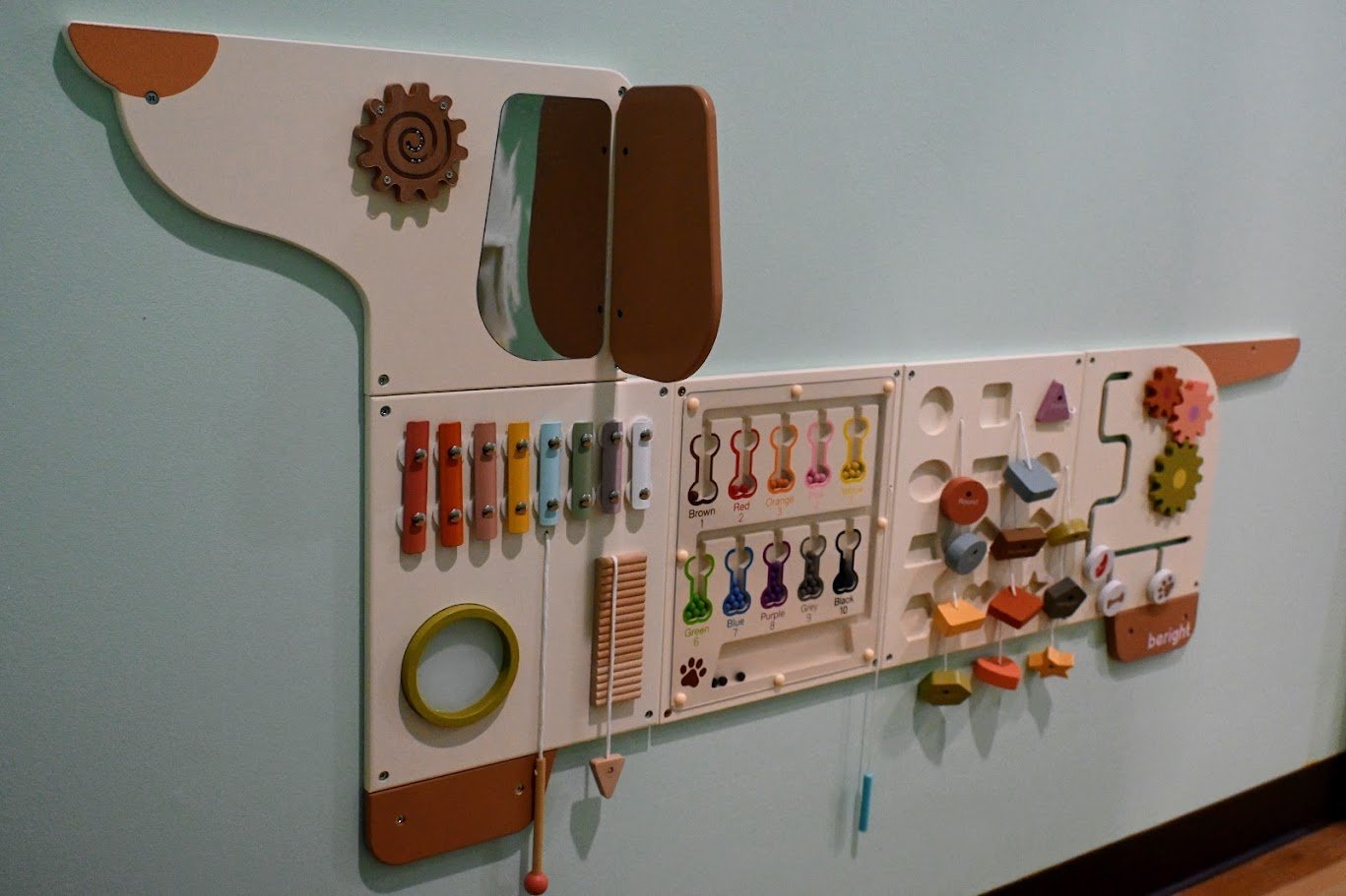 Mounted sensory activity wall with tactile and fine-motor play elements.