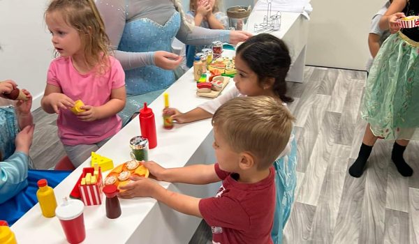 Kids gathered around a pretend-play setup at Giggle Town.