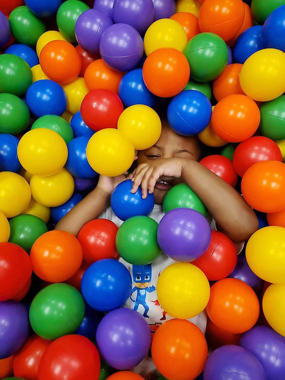 Child playing in a bright ball pit at GO WILD! Family Fun Zone.