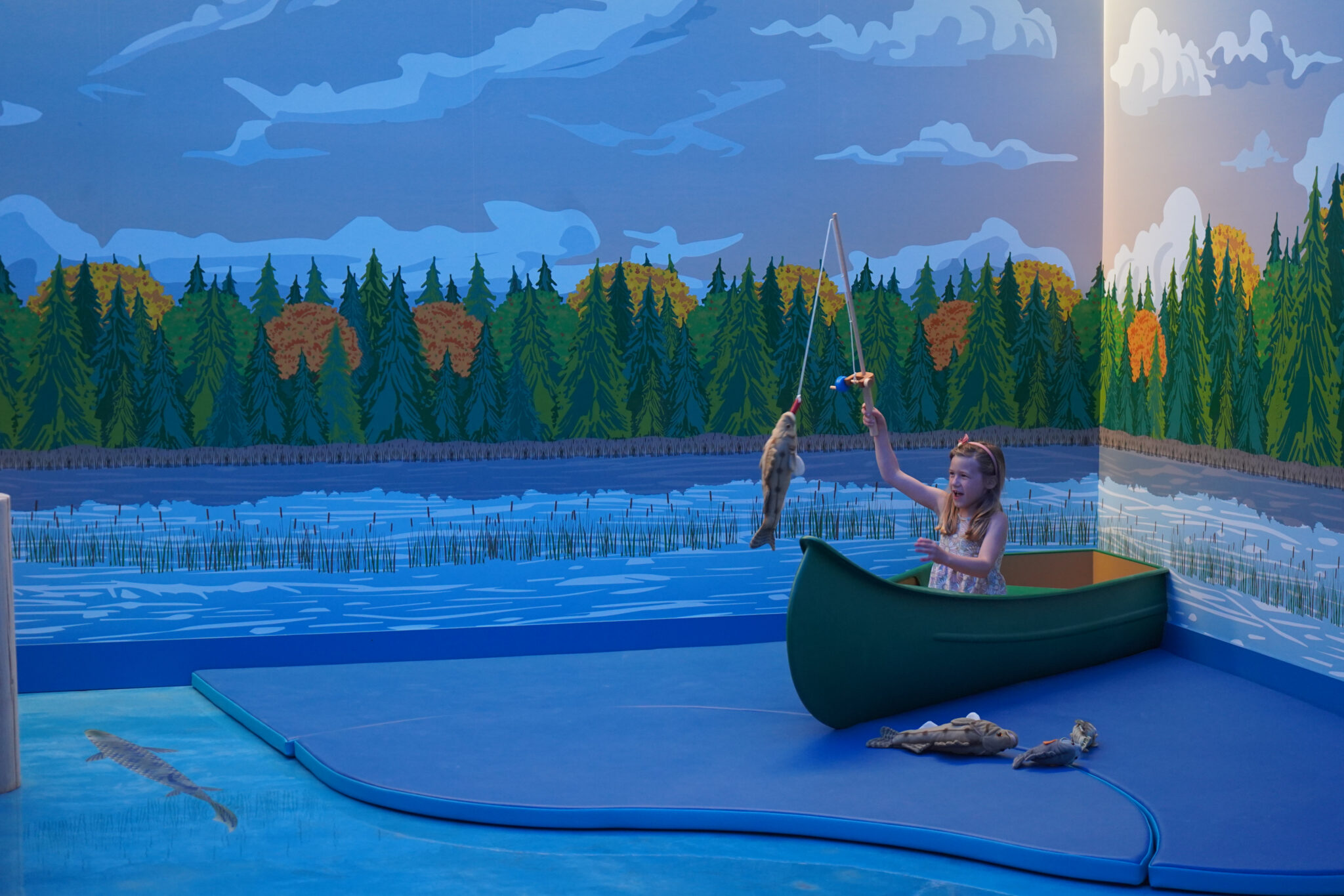 A child playing in a canoe-themed exhibit at Great River Children's Museum.