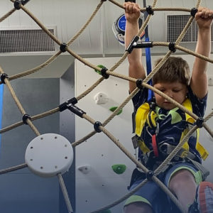 Child navigating a rope climbing feature at Play Climb.