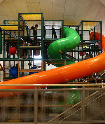 Large multi-level play structure with tube slides inside Holland Playland.